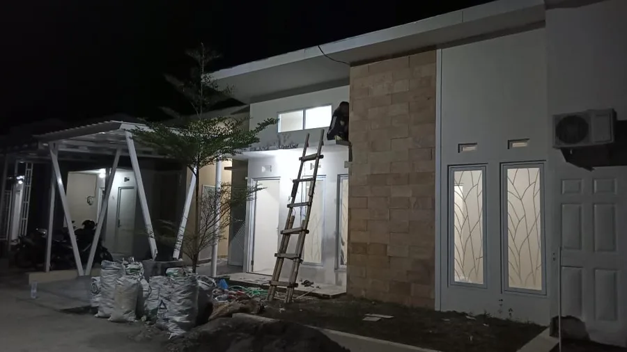 A finished house at night, with stone cladding and a carport