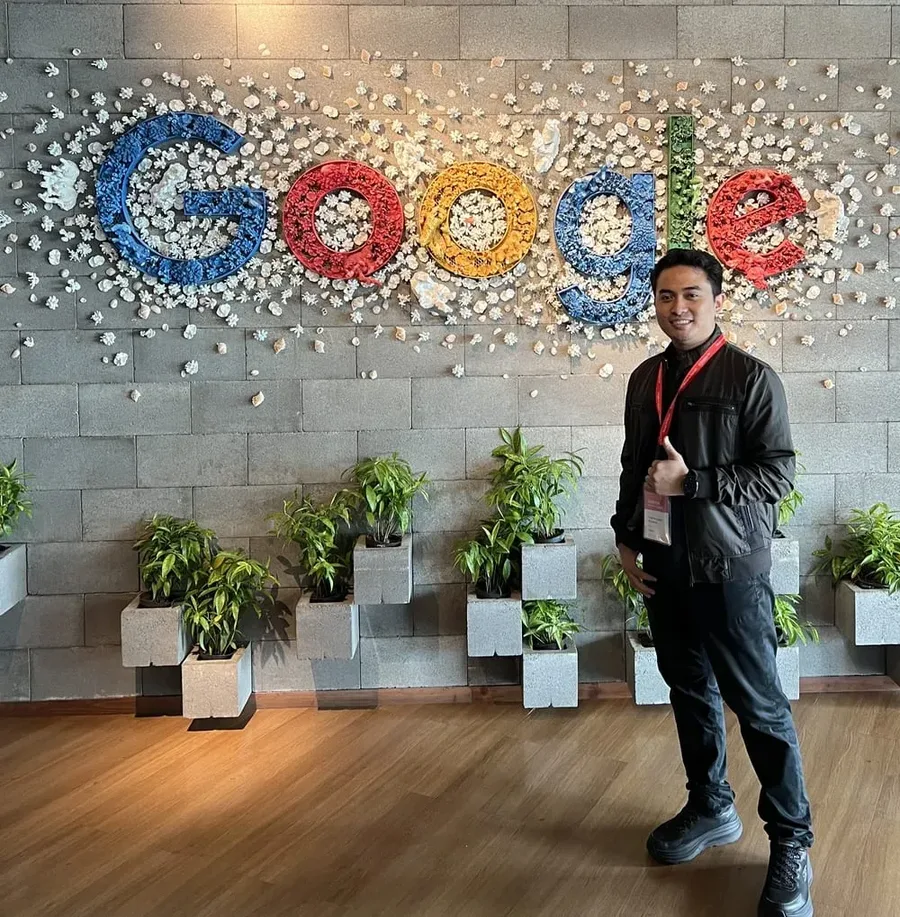 Nugraha Labib Mujaddid in front of the Google logo wall at the Google office